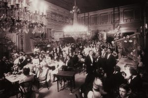 Uppklädda människor har samlats inne i Börsens festsal år 1895.