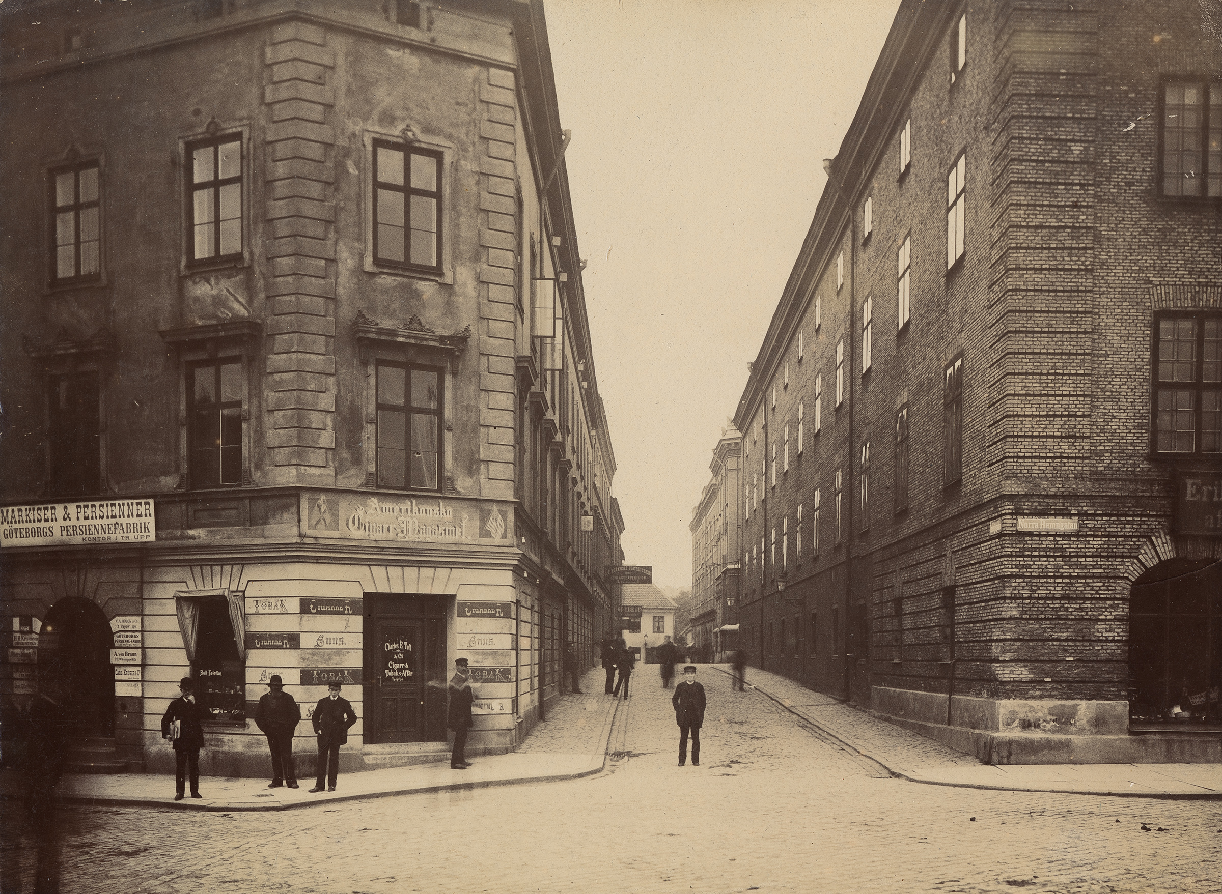 Flera personer står vid Korsningen Smedjegatan - Norra Hamngatan och kollar in i kameran år 1888.